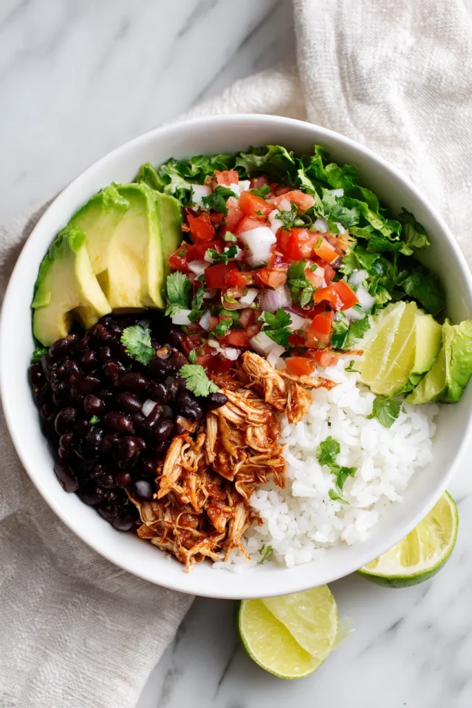 Taco bowl with chicken, rice, beans, and pico under bright natural kitchen light.